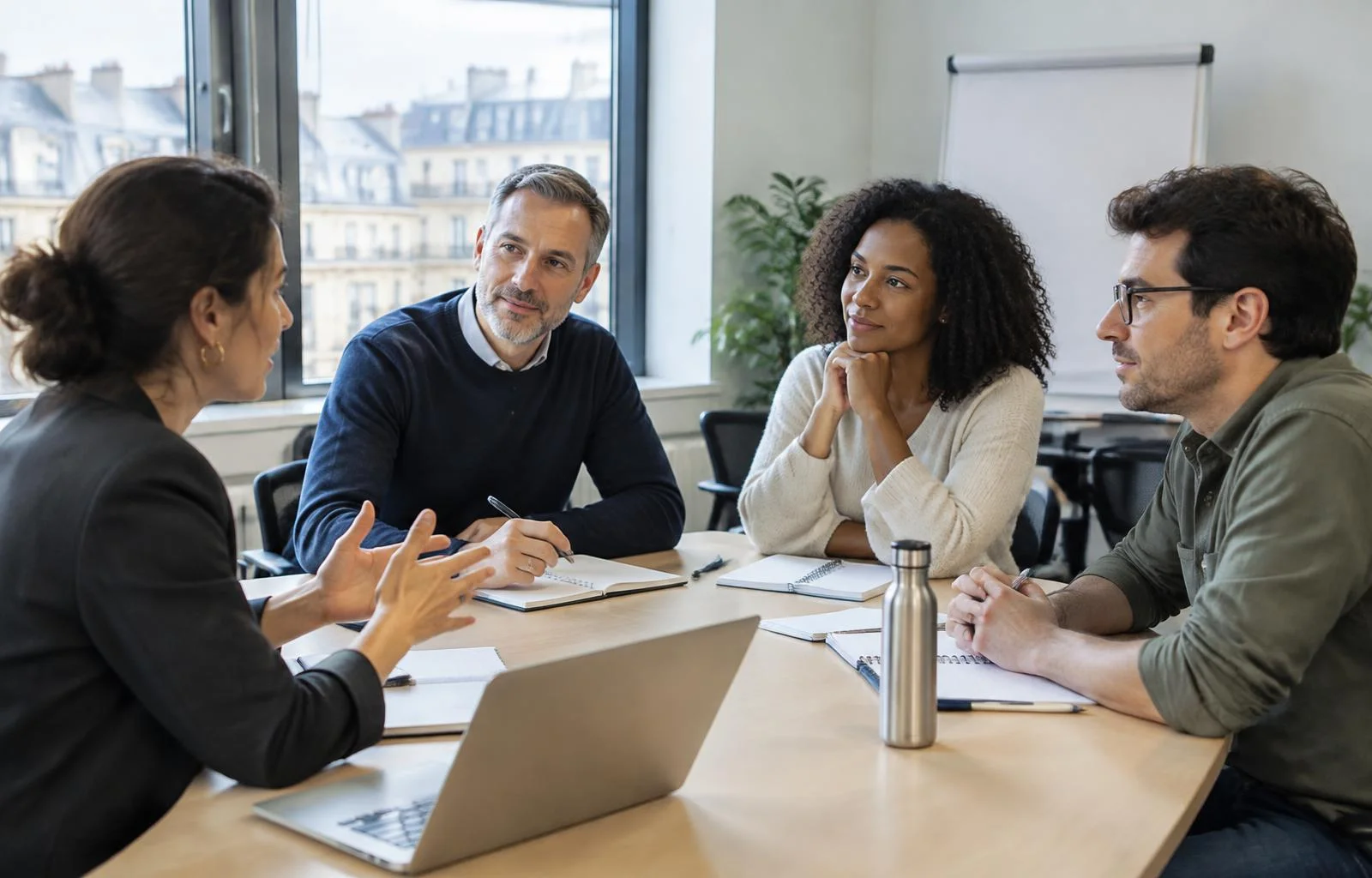 Un formateur anime une mise en situation avec un petit groupe de managers autour d'une table, pendant la formation management d'équipe en petit groupe.