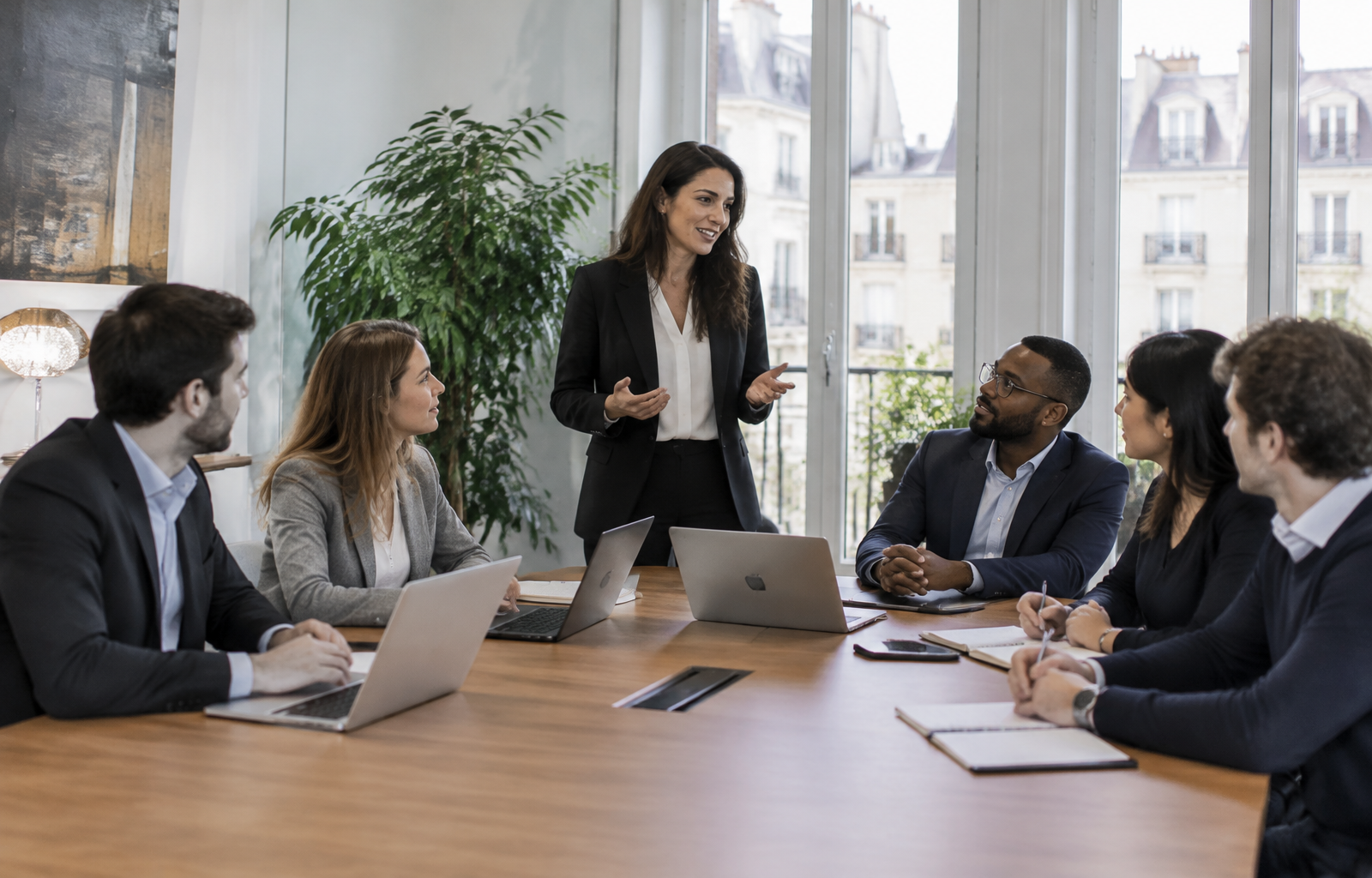 Une manager anime une réunion avec son équipe autour d'une table, une situation de leadership travaillée en formation management d'équipe.